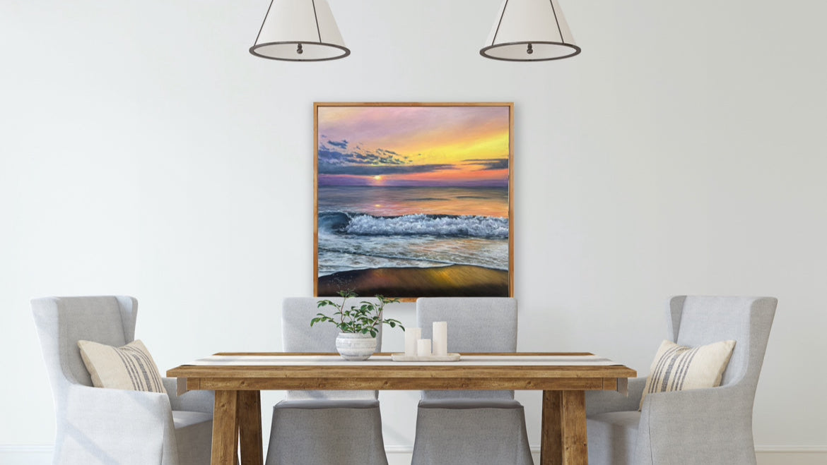 Dining room with wooden table and chairs, featuring a framed artwork of a sunset over water on the wall.